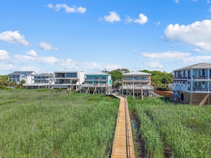 A coastal property with multiple buildings, a wooden boardwalk, and a grassy field.