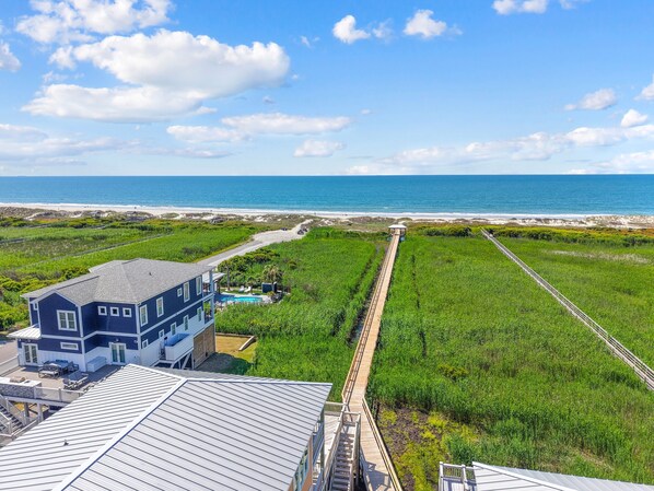 A coastal property with a large house, a wooden deck, and a view of the ocean.