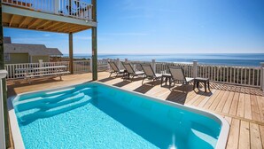 A pool with lounge chairs and a view of the ocean. - Beach Landing: Spacious 7BR/6BA Oceanfront retreat in Oak Island, sleeps 22 with private pool. (Oak Island)