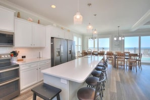 Uma cozinha moderna com armários brancos, eletrodomésticos de aço inoxidável e uma ilha central com banquetas.