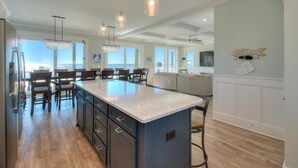 A spacious kitchen with a large island, pendant lighting, and a view to the outside.