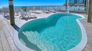 A hot tub on a wooden deck with lounge chairs and a 'No Diving' sign.