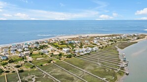 An aerial view of a coastal residential area with houses, a beach, and a bridge leading to a marina. - Bring a Boat! Oceanview/Soundfront Retreat with Gameroom/Pool/HT (Oak Island)