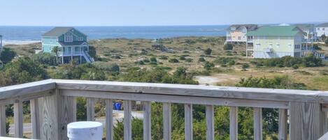 Une vue sur la côte, depuis une terrasse en bois donnant sur les maisons et l’océan.
