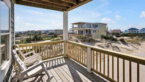 A wooden deck with chairs, overlooking a beach with houses in the background. - Bring a Boat! Oceanview/Soundfront Retreat with Gameroom/Pool/HT (Oak Island)