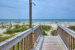 A wooden boardwalk leading to a beach with a clear view of the ocean and beachgoers. - Wave Rider: Oceanfront 4BR house in Oak Island, sleeps 12, pet-friendly! (Oak Island)