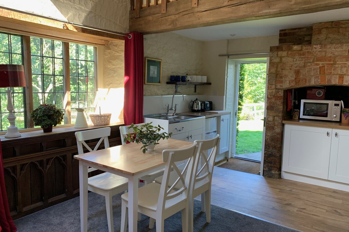 A cozy kitchen with a wooden table and chairs, a sink, and a microwave.