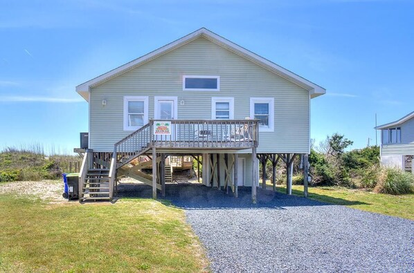 A two-story house with a balcony, a staircase, and a gravel driveway.