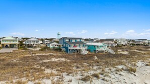 Zona residencial costera con casas frente a la playa, terreno arenoso y un depósito de agua.