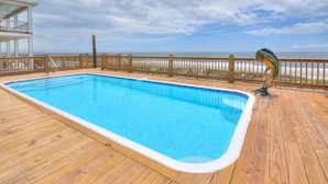 A rectangular swimming pool with a wooden deck and a wooden fence. - Bright Horizons: Experience oceanfront luxury in this 7-bedroom, 6-bath retreat in Oak Island! (Oak Island)