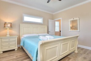 A bedroom with a bed, a nightstand, a lamp, a window, and a mirror.