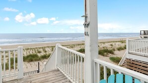 A wooden deck with white railings overlooking a beach. - Experience oceanfront luxury at Cordoba, a spacious 7-bedroom retreat in Oak Island! (Oak Island)