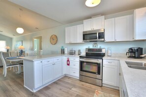 Una cocina moderna con muebles blancos, electrodomésticos de acero inoxidable y una isla central.