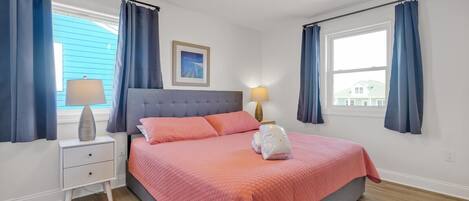 A bedroom with a bed, two bedside tables, a ceiling fan, and a window with curtains.