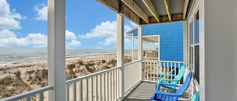 A beach house with a covered porch, blue exterior, and beach view.