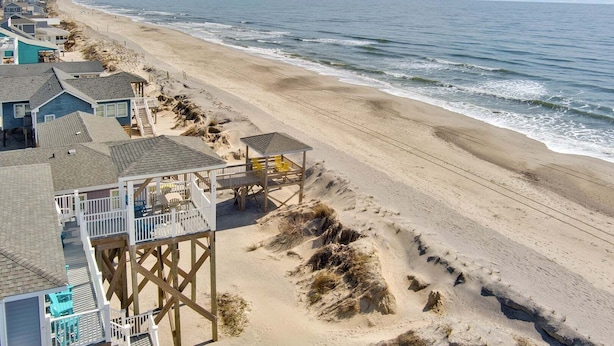 Une propriété située en bord de mer, dotée d’une terrasse en bois, d’une tour de surveillance pour les sauveteurs et offrant une vue sur l’océan.