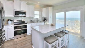 Una cocina moderna con armarios blancos, electrodomésticos de acero inoxidable y una isla grande con taburetes de bar.