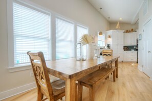 A kitchen with a wooden table, chairs, and white cabinets. - Experience beachfront luxury at Fishizzle in Oak Island, perfect for family getaways. (Oak Island)