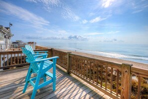 A wooden deck with a railing overlooking a beach. - Experience beachfront luxury at Fishizzle in Oak Island, perfect for family getaways. (Oak Island)