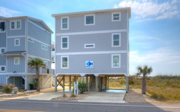 A multi-story building with a sign indicating a fish-themed establishment. - Experience beachfront luxury at Fishizzle in Oak Island, perfect for family getaways. (Oak Island)