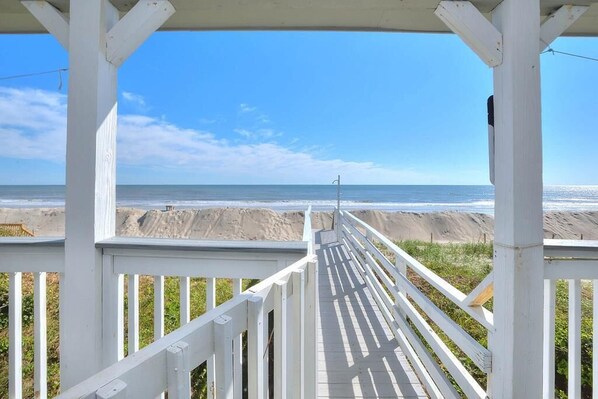 A wooden deck with a view of the beach and ocean.