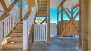 A spacious interior with a wooden staircase, white railings, and a view of the outside. - Discover Gypsea, a spacious 4-bedroom oceanview home in Oak Island, perfect for 10 guests! (Oak Island)