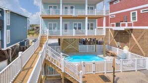 Ein mehrstöckiges Hotel mit Poolbereich, Balkonen und einer Holzterrasse.