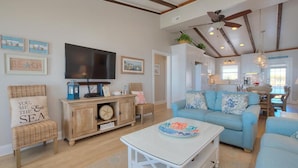 Un salón amplio con un televisor grande, un sofá azul y un mueble de madera.