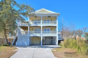 A multi-story building with a covered front porch and a garage.