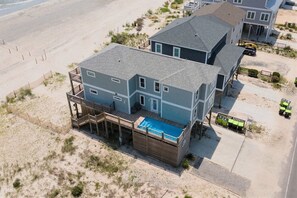 A two-story beachfront house with a swimming pool, a covered deck, and a boat dock.