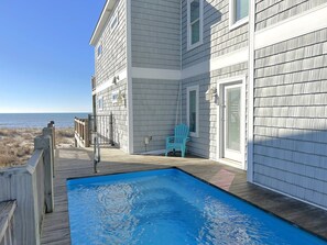 A two-story house with a wooden deck and a swimming pool.