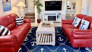 Een woonkamer met rode leren banken, een houten salontafel, een televisie en een plant in pot.