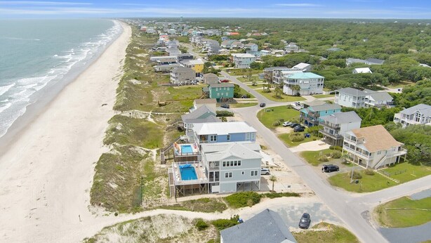 A coastal residential area with houses, a beach, and a clear sky. - Experience ocean views at Oak Island's 4-bedroom Kelly Dawn, perfect for 10 guests! (Oak Island)