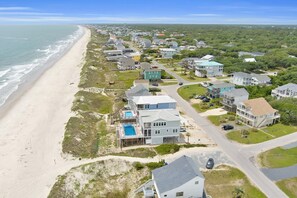 A coastal residential area with houses, a beach, and a clear sky. - Experience ocean views at Oak Island's 4-bedroom Kelly Dawn, perfect for 10 guests! (Oak Island)
