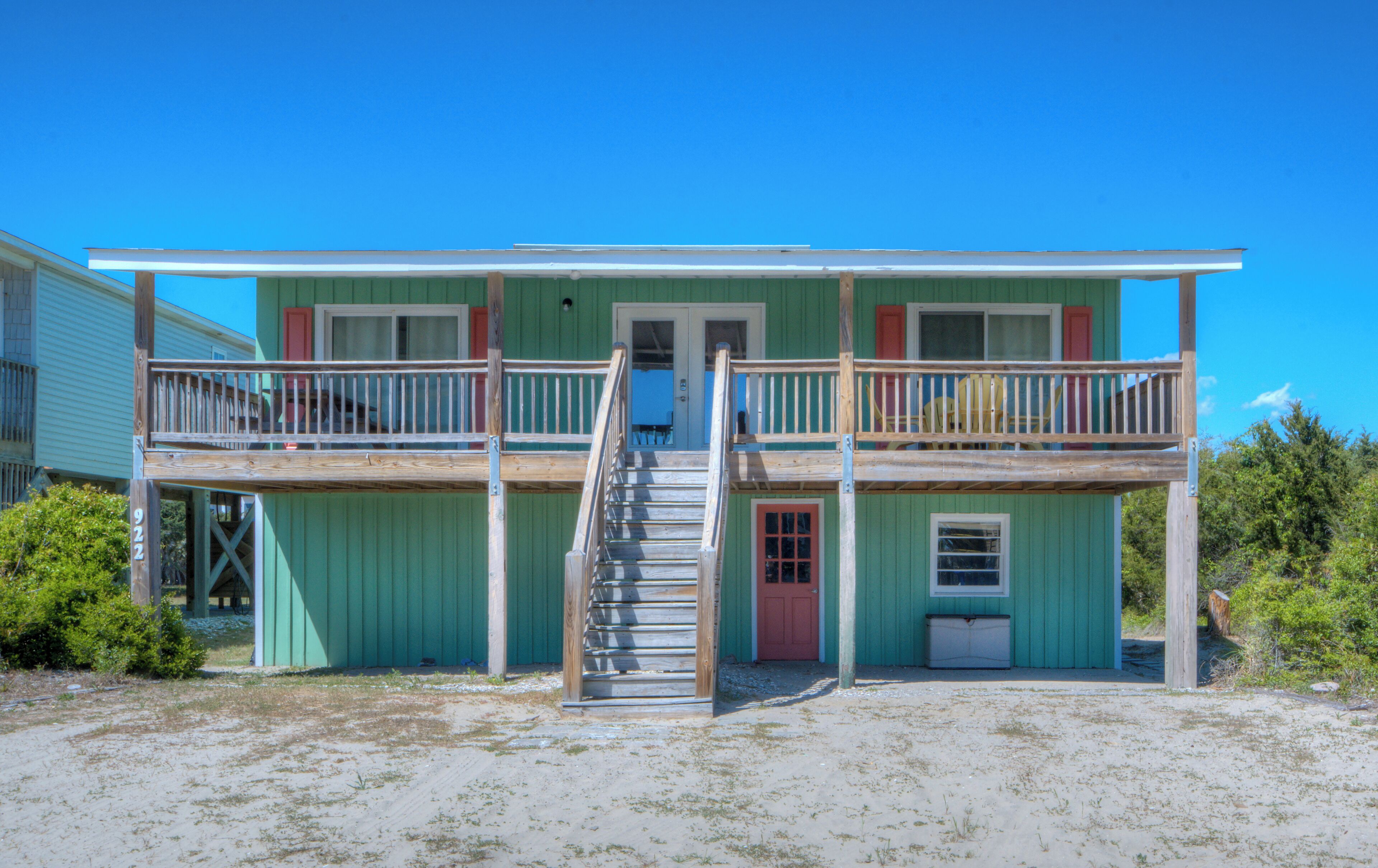 A two-story building with a balcony, a staircase, and a door.