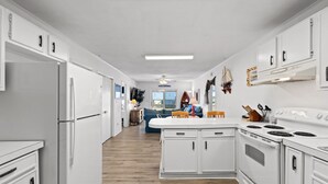A modern kitchen with white cabinetry, a central island, and a stove.