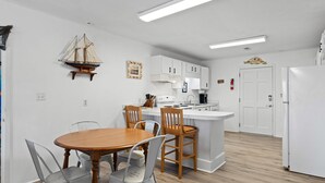 A compact kitchen with white cabinets, a wooden dining table, and a small island.