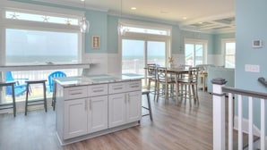 A spacious kitchen with a large island, white cabinetry, and a view of the ocean. - Experience luxury in this oceanfront 5-bedroom retreat in Oak Island. (Oak Island)