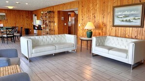 Ein Zimmer mit zwei weißen Sofas, einem Esstisch mit Stühlen, einer Lampe und einem Bild an der Wand.