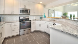 A modern kitchen with white cabinets, stainless steel appliances, and a granite countertop. - Oceanfront Monkeytyme in Oak Island: 5BR, 4BA, sleeps 13, perfect for families! (Oak Island)