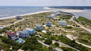 Vista aérea de una zona residencial costera con casas, una playa y una carretera.