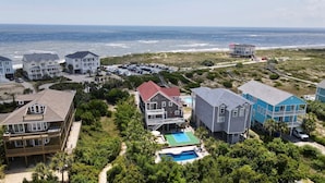 Zona residencial costera con propiedades frente al mar, una piscina y una playa al fondo.