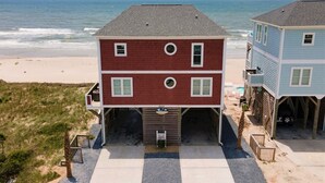 A two-story beach house with a front porch, a garage, and a view of the ocean. - Experience oceanfront luxury at 'No Worries,' an ideal 5-bedroom retreat in Oak Island. (Oak Island)