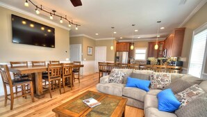 A spacious living room with a large sectional sofa, a wooden coffee table, and a dining area with a wooden table and chairs. - Experience oceanfront luxury at 'No Worries,' an ideal 5-bedroom retreat in Oak Island. (Oak Island)