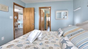Ein Schlafzimmer mit einem Bett, einem Spiegel und einer Tür zu einem Badezimmer.