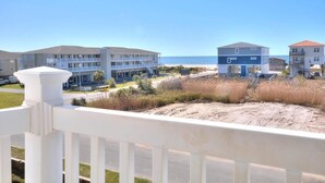 Una propiedad frente a la playa con varias edificaciones, una playa de arena y un cielo azul despejado.
