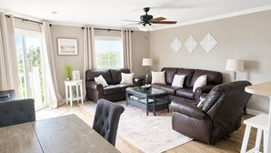 A living room with a sofa set, a coffee table, a dining table, and a ceiling fan.