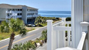 A multi-story building with balconies overlooking a road and ocean view. - Experience ocean views at Oak Island OW 3204, a spacious 3-bedroom condo ideal for 10 guests. (Oak Island)
