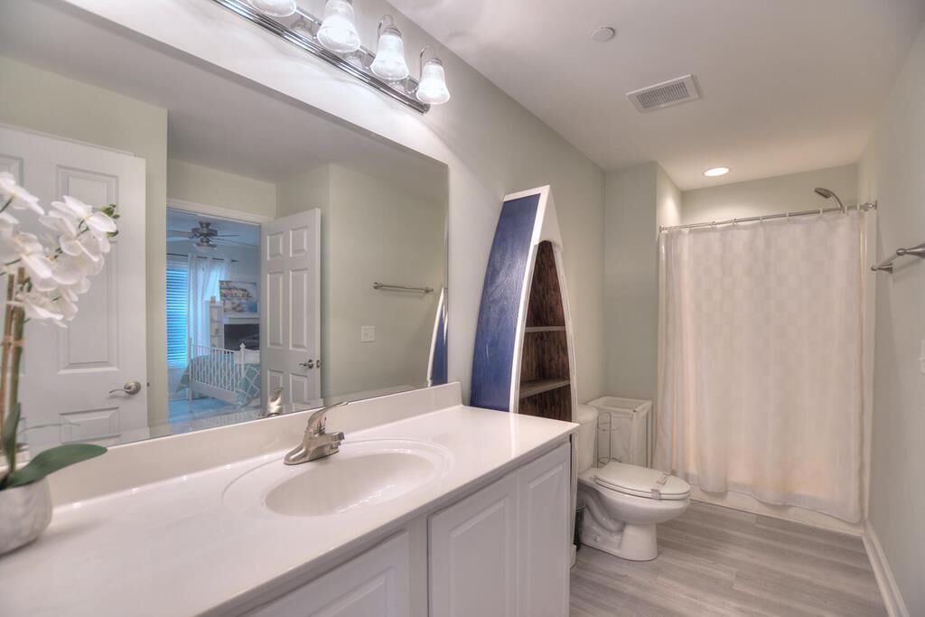 A bathroom with a white sink, a large mirror, a toilet, and a shower curtain.