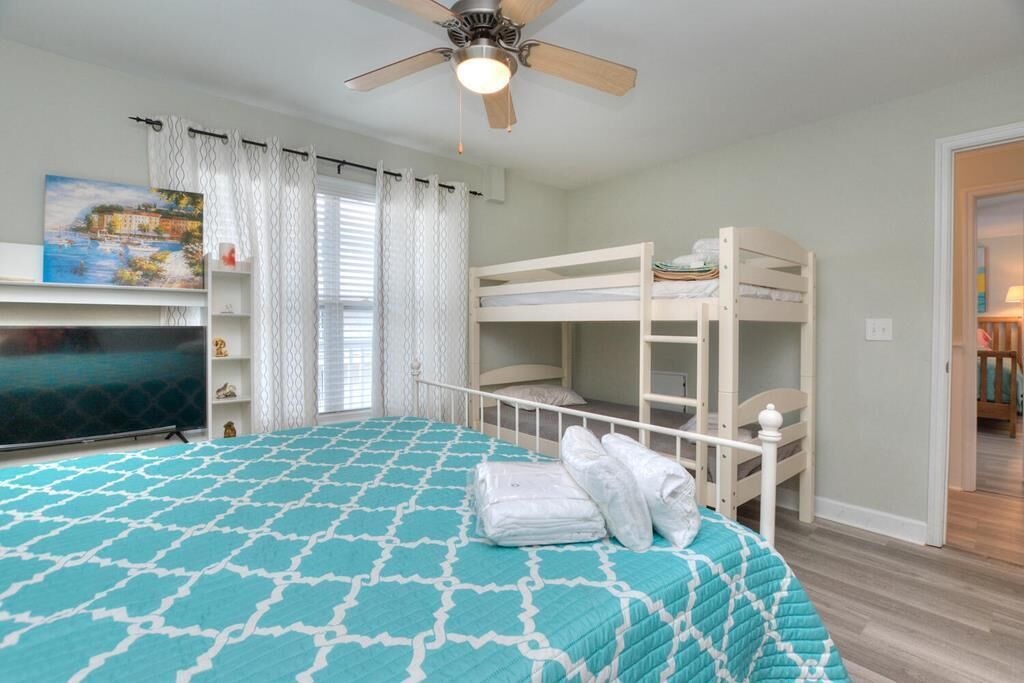 A bedroom with a bunk bed, a TV, and a ceiling fan.